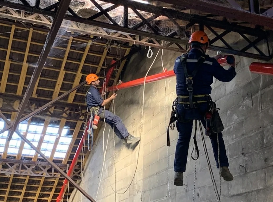 Técnico realizando inspección y reparación en estructura interior de nave industrial